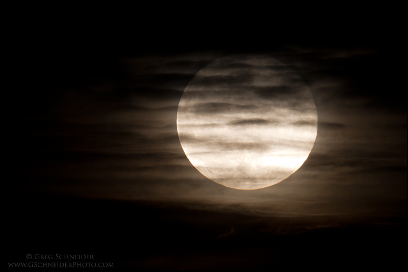 Full moon behind partial cloud